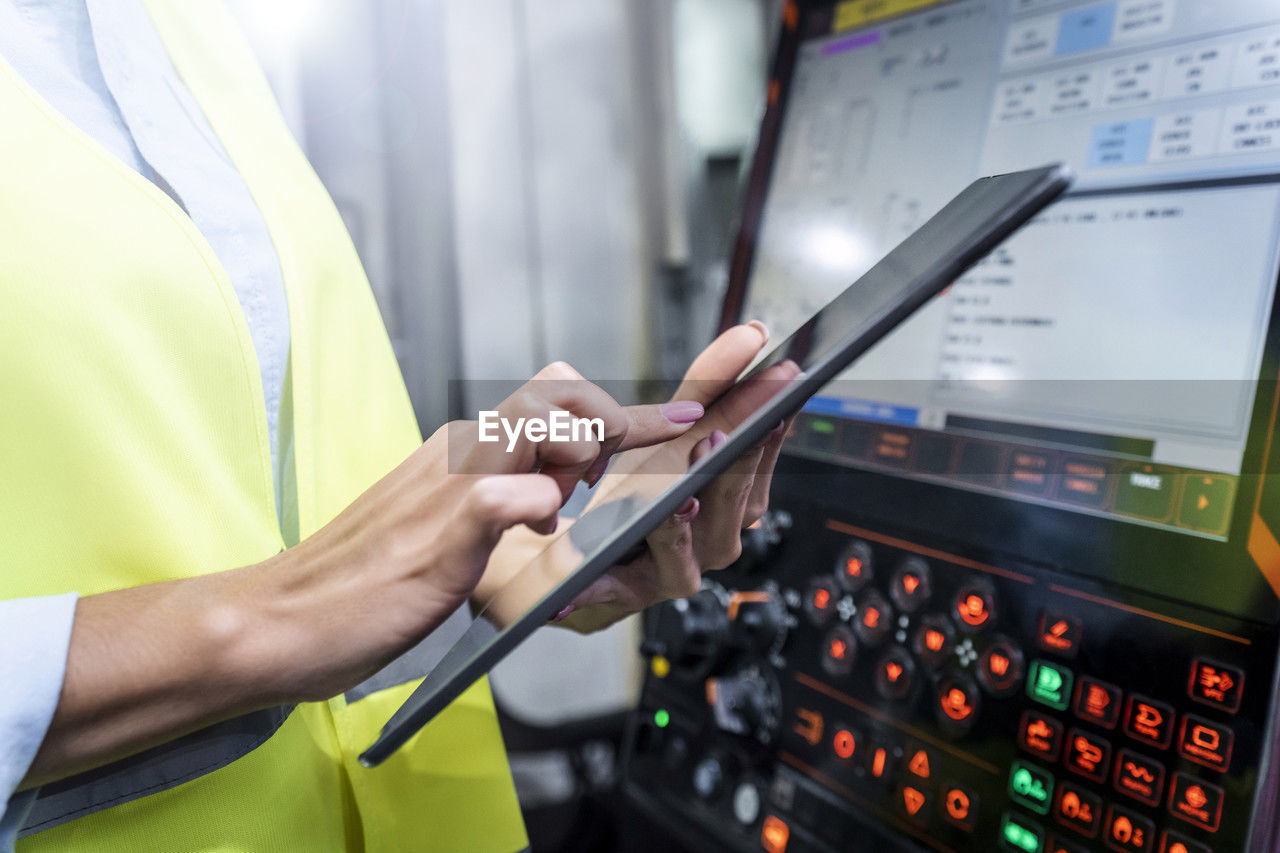 Hands of engineer using tablet pc by machine in industry