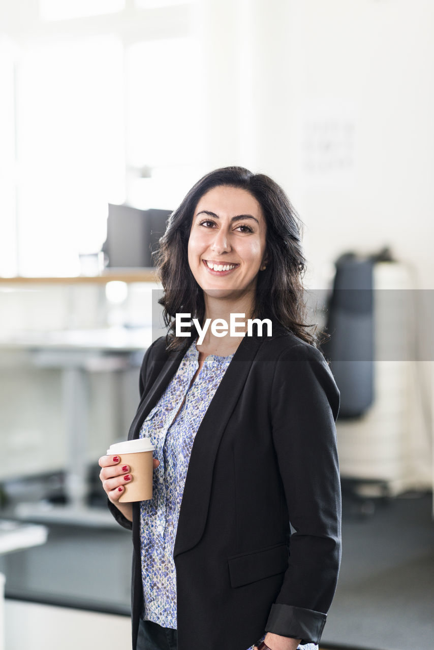 Young businesswoman in office with coffee