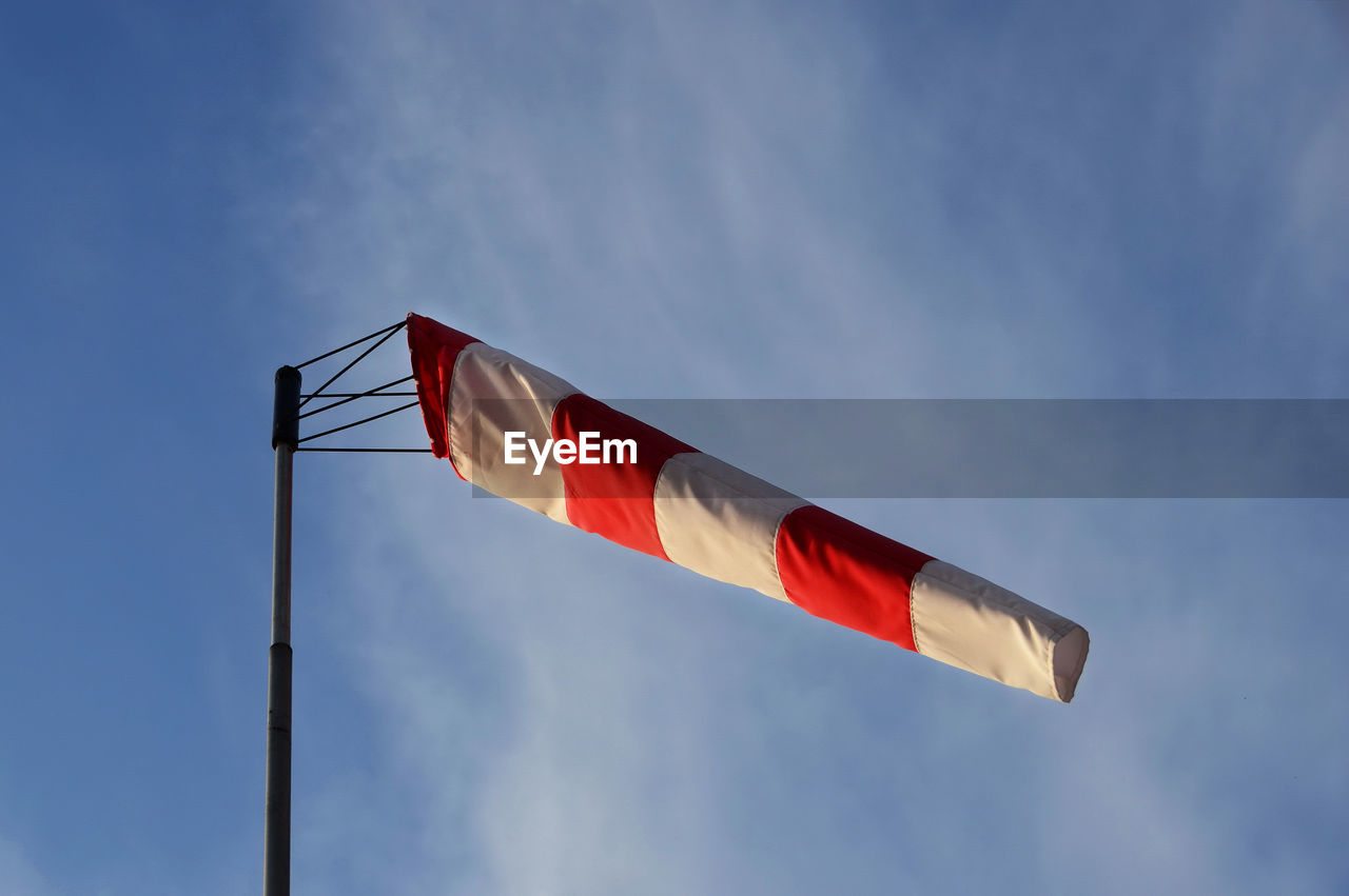Wind cone weather vane on windy day with blue sky in the background.