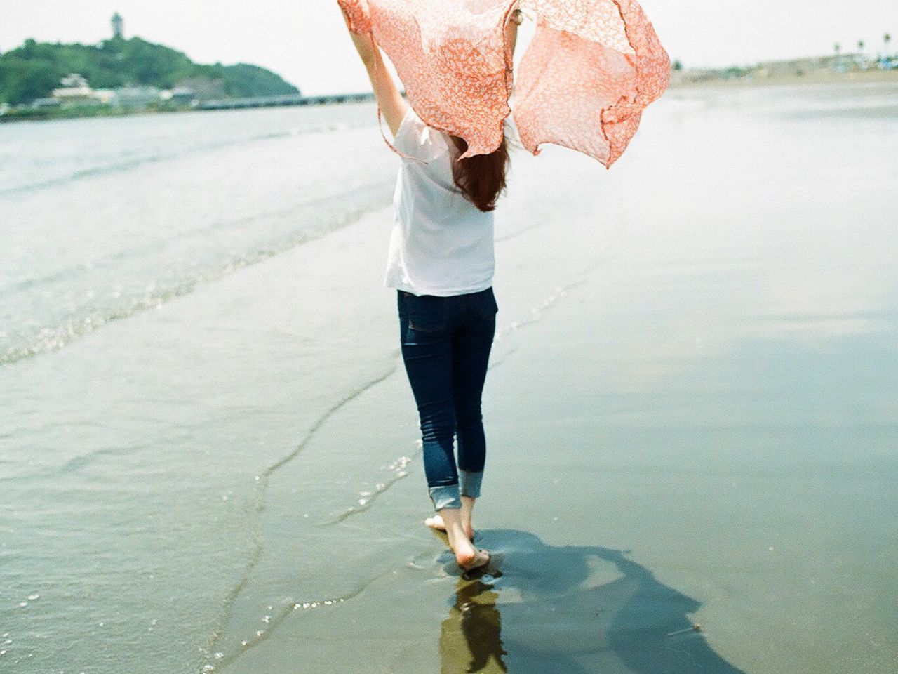 Woman with headscarf walking at beach