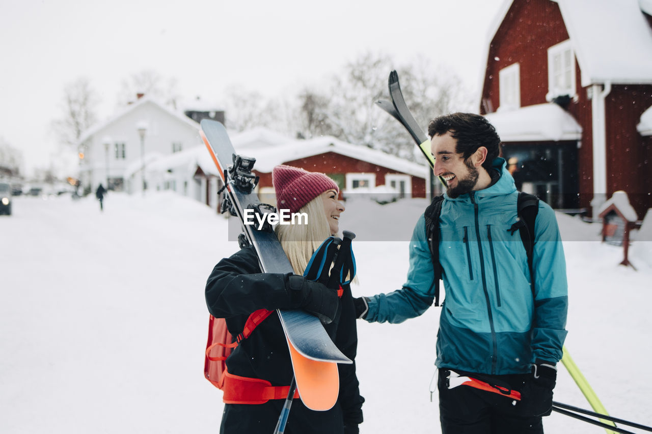 Cheerful male and female friends looking at each other during winter