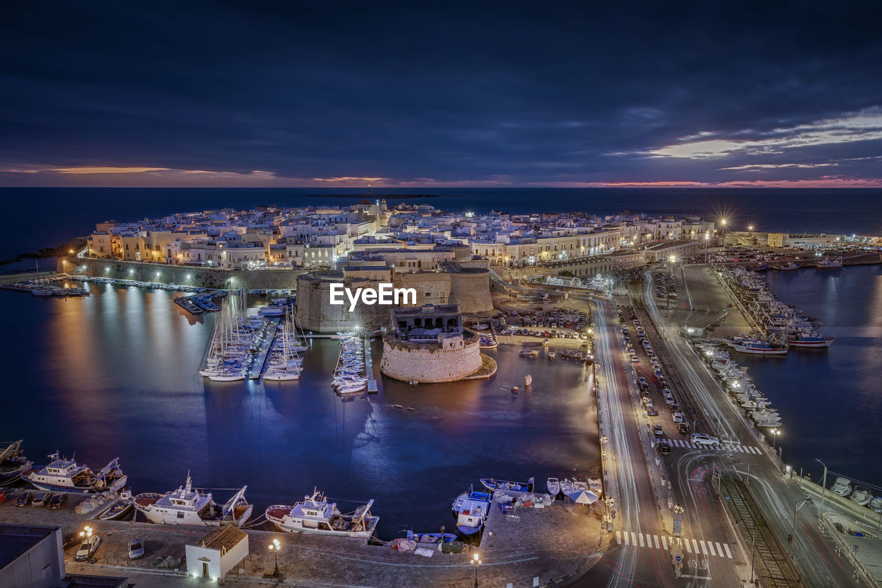 HIGH ANGLE VIEW OF ILLUMINATED CITYSCAPE AGAINST SKY AT NIGHT