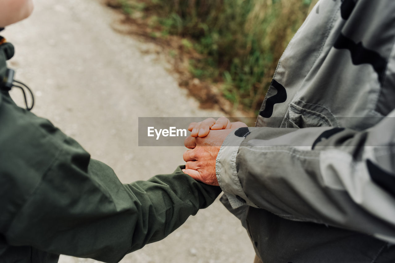 Man and boy hold hands tightly in military tourist clothing. friendly relations between generations