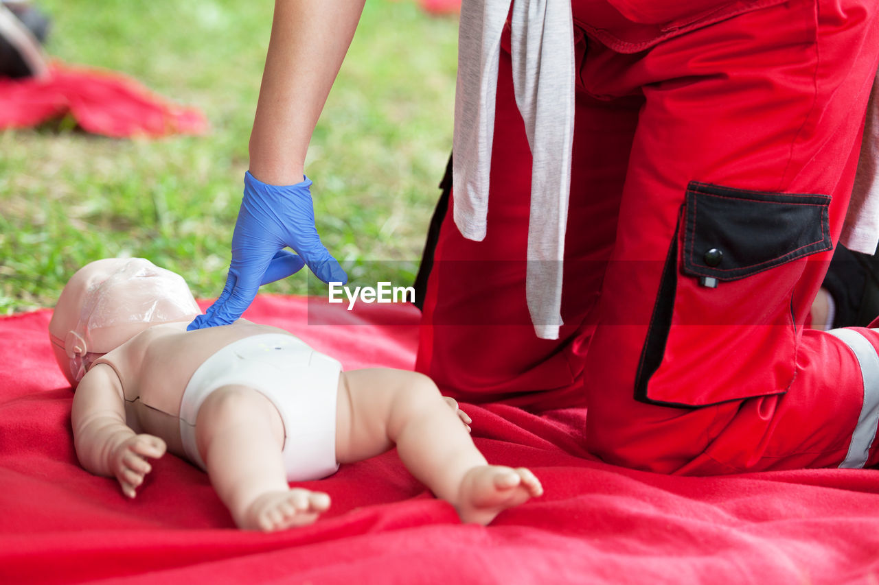 Midsection of paramedic practicing on cpr dummy at blanket