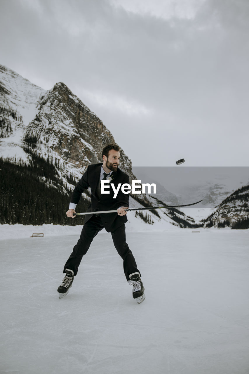 Hockey player with suit on juggles puck on frozen lake in mountains