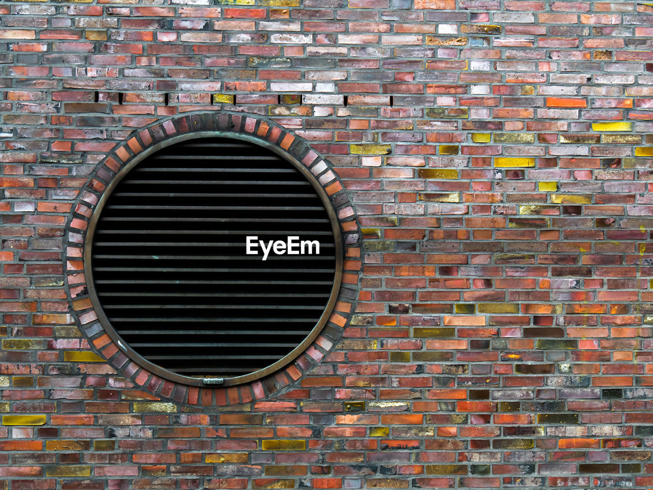 FULL FRAME SHOT OF BRICK WALL WITH BUILDING IN BACKGROUND