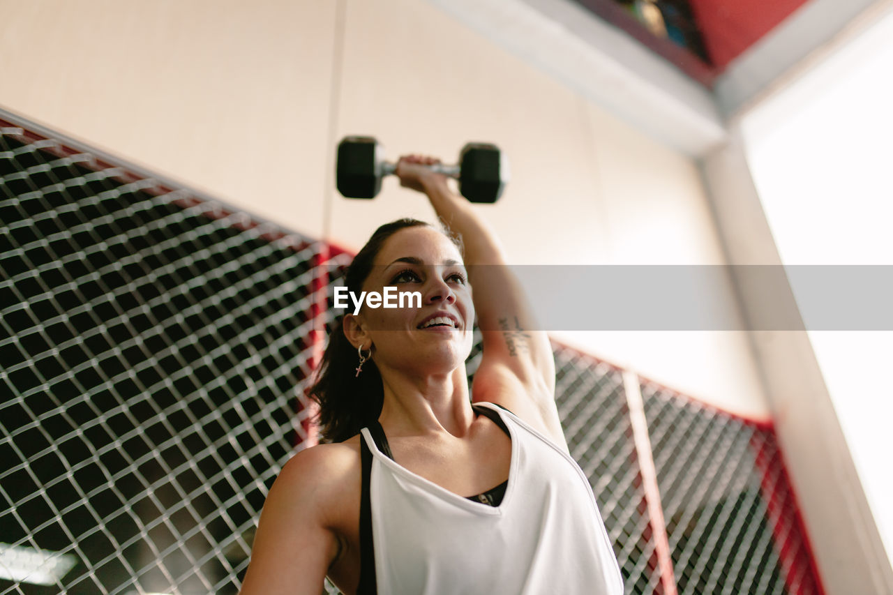 Low angle view of woman lifting dumbbell in gym