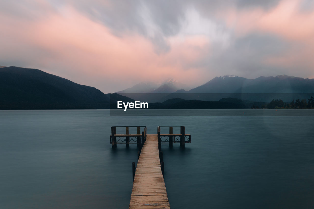 Pier on lake against sky during sunset