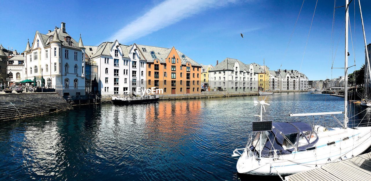 View of buildings by canal against cloudy sky