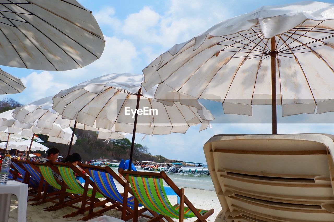 PANORAMIC VIEW OF LOUNGE CHAIRS AND PARASOLS ON BEACH