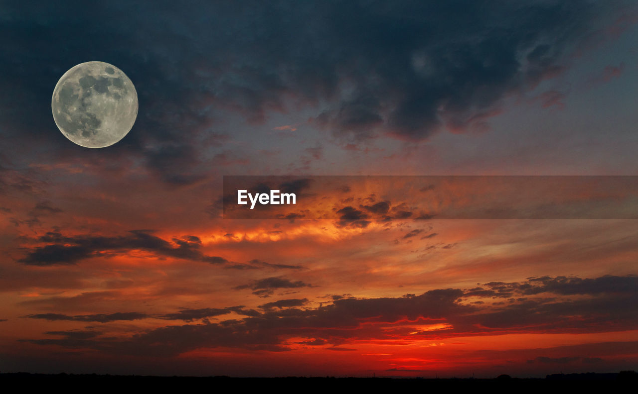 LOW ANGLE VIEW OF MOON IN SKY AT SUNSET