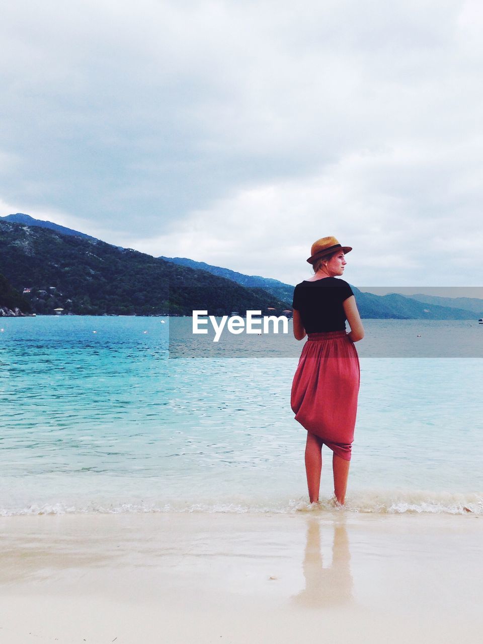 Rear view of woman looking away while standing at beach