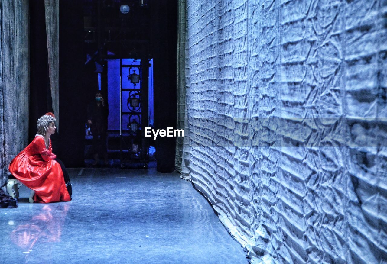 Side view of woman sitting in corridor