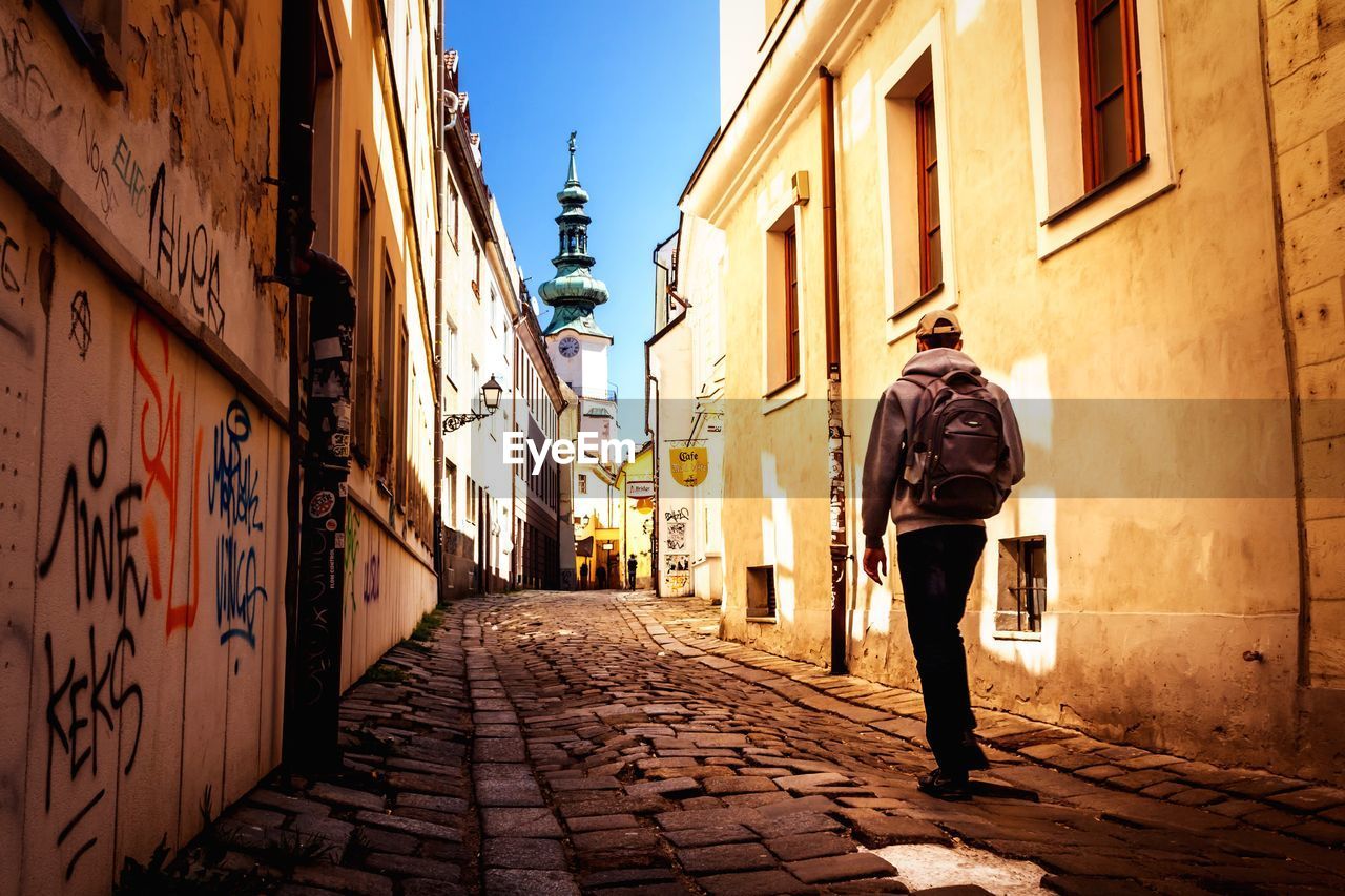 Man walking on road along buildings