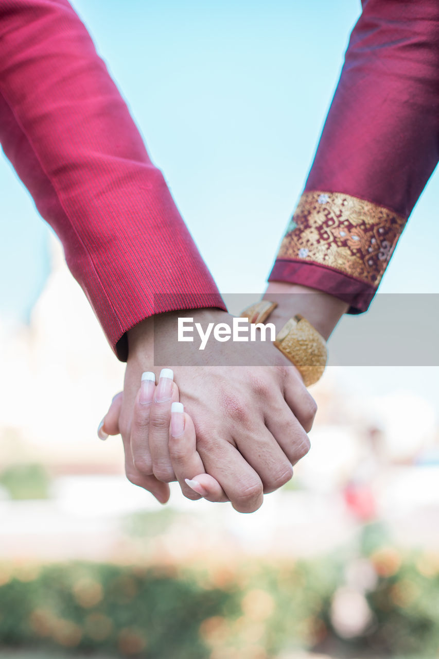 Cropped image of bride and bridegroom holding hands during wedding ceremony