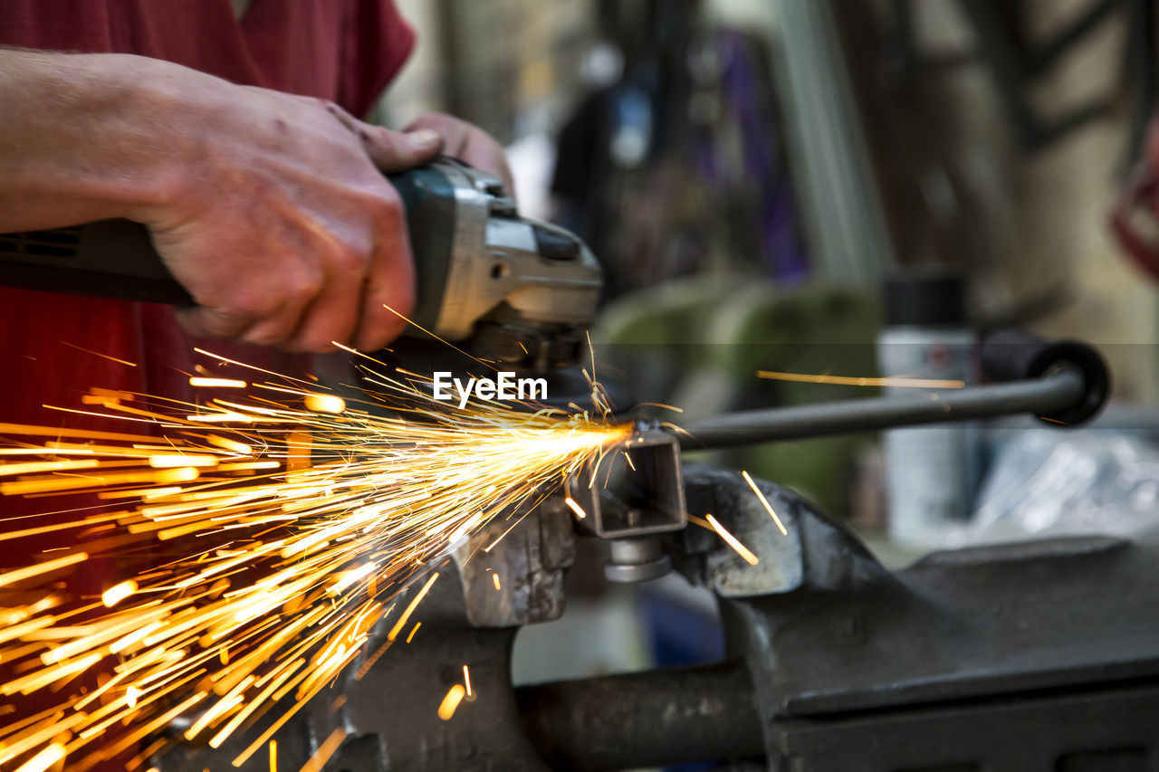 Midsection man grinding metal in factory