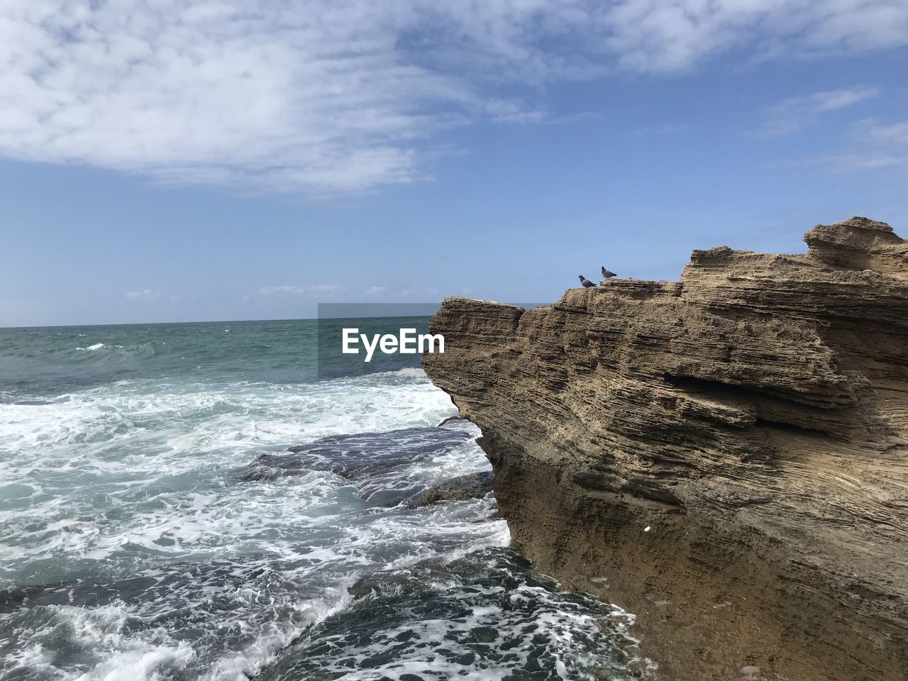 ROCK FORMATION ON SEA SHORE AGAINST SKY