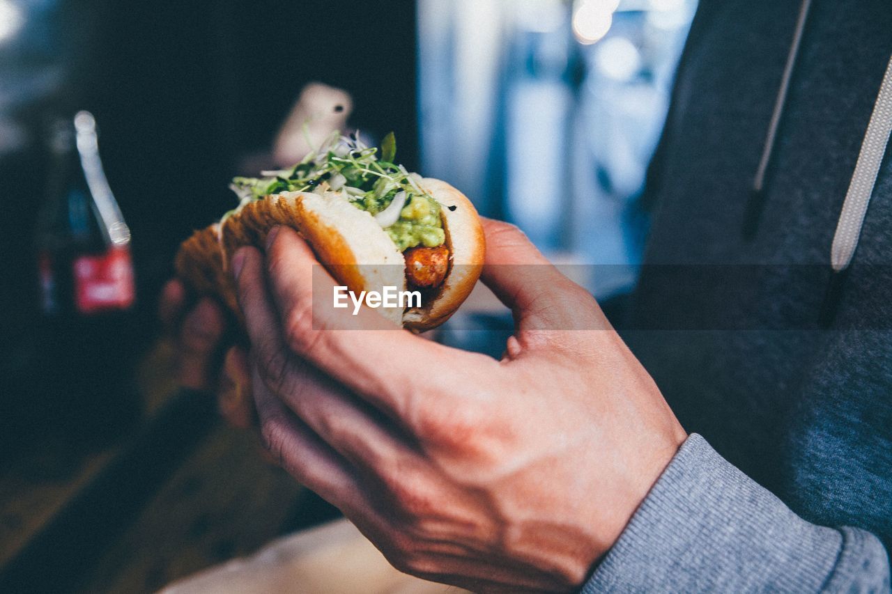 Cropped image of man eating hot dog