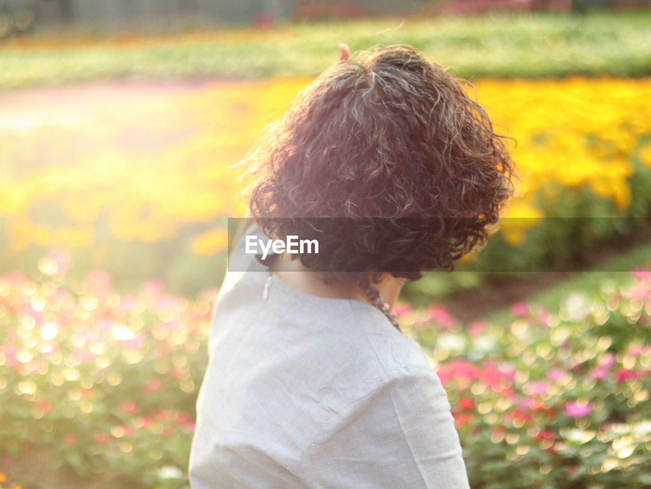 Side view of woman standing against flowering plants