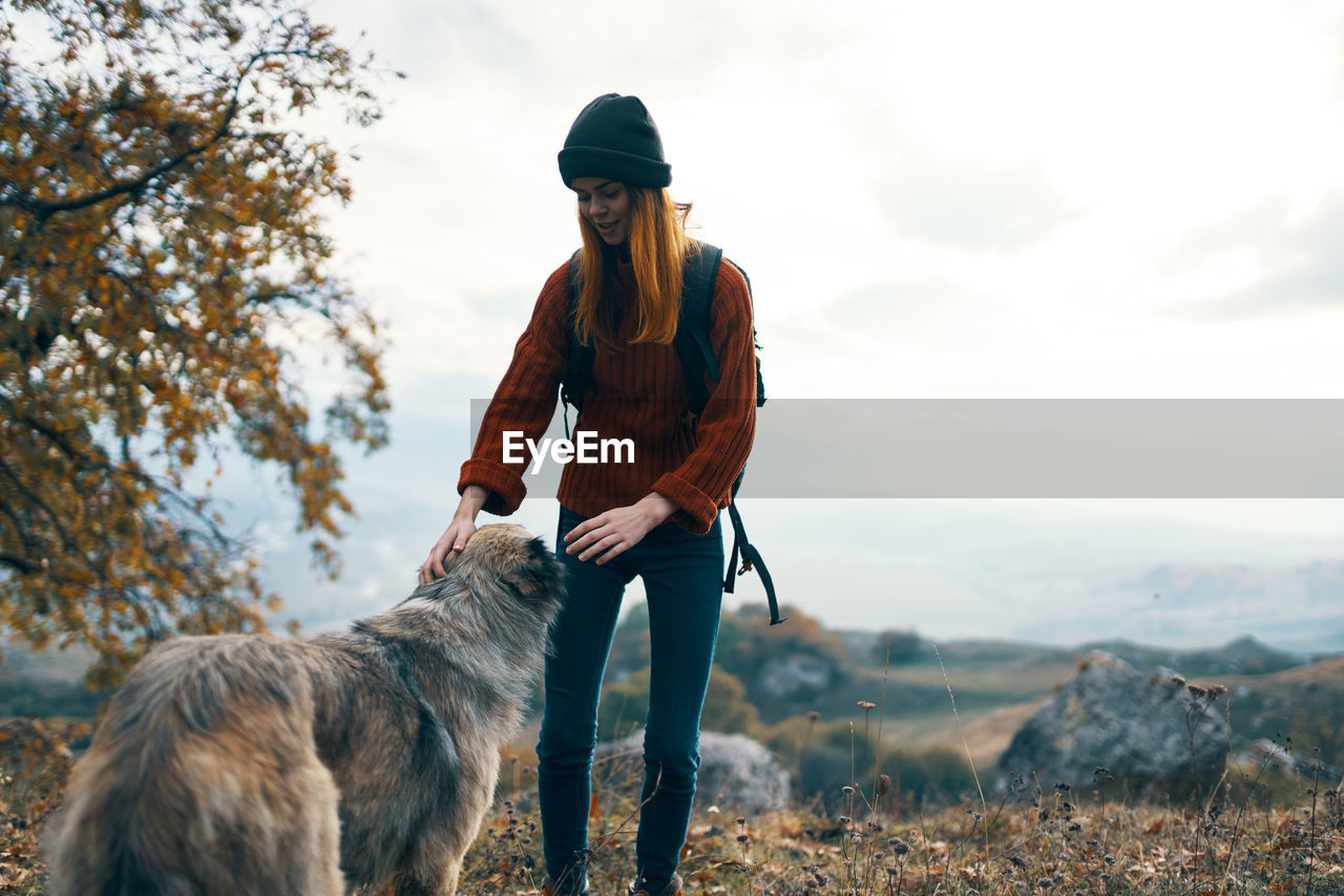 REAR VIEW OF PERSON STANDING WITH DOG