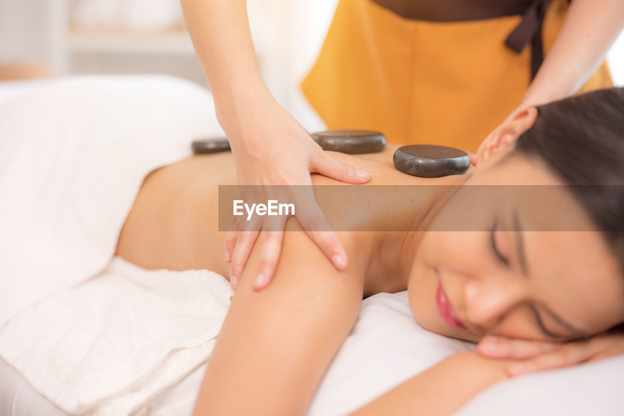 In a spa salon, a young woman enjoys massage therapy.