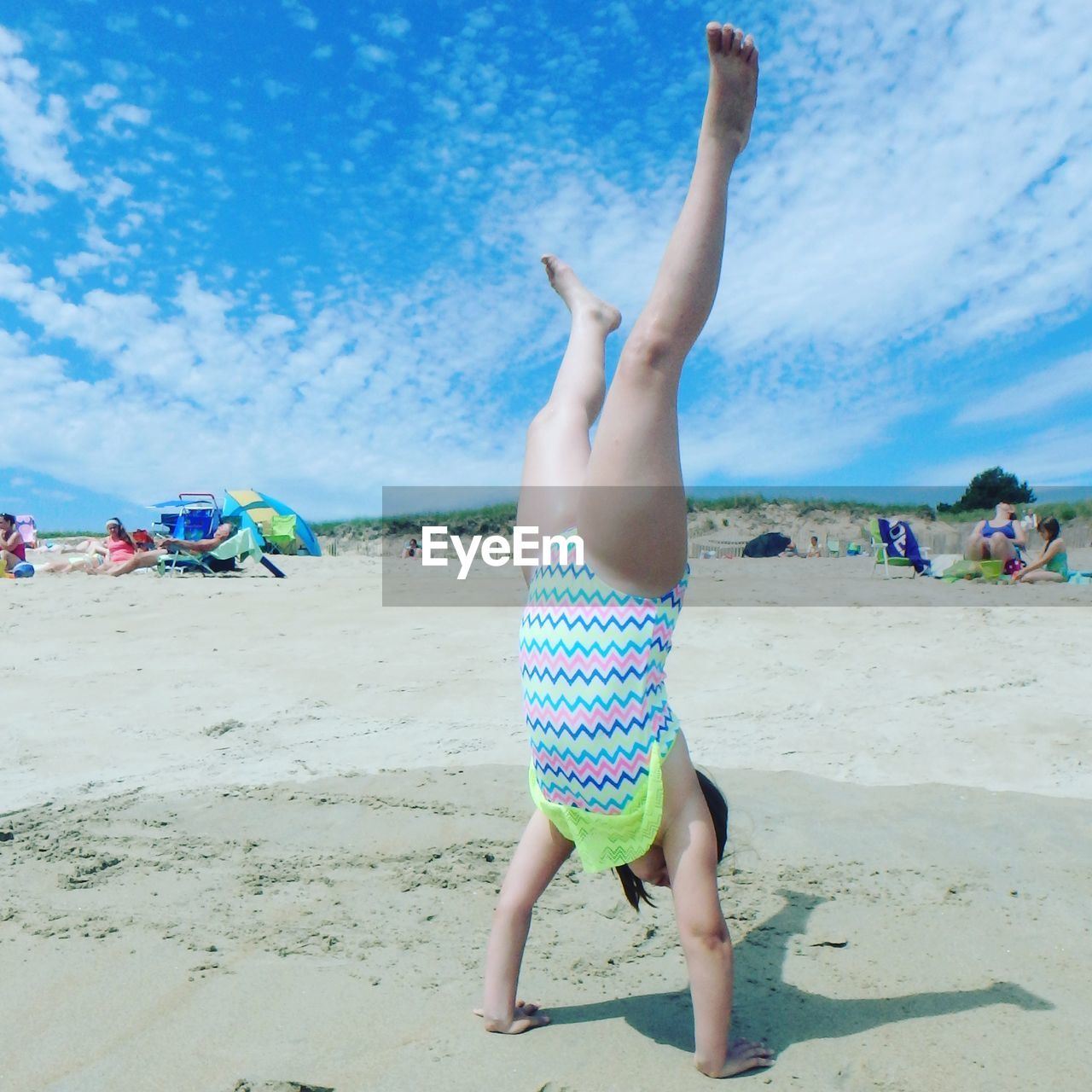 Full length of girl doing handstand on beach against sky