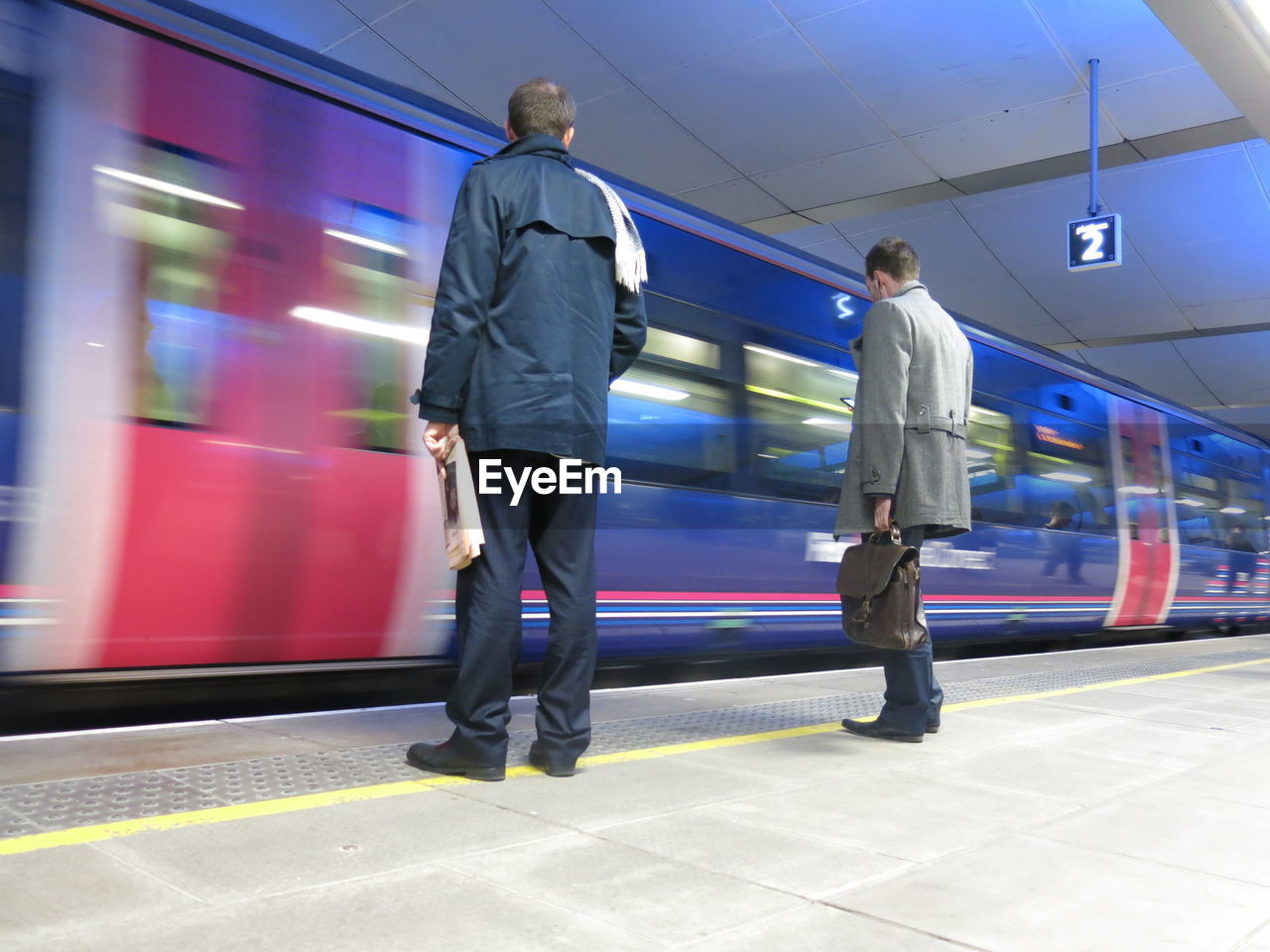 Rear view of men waiting for train