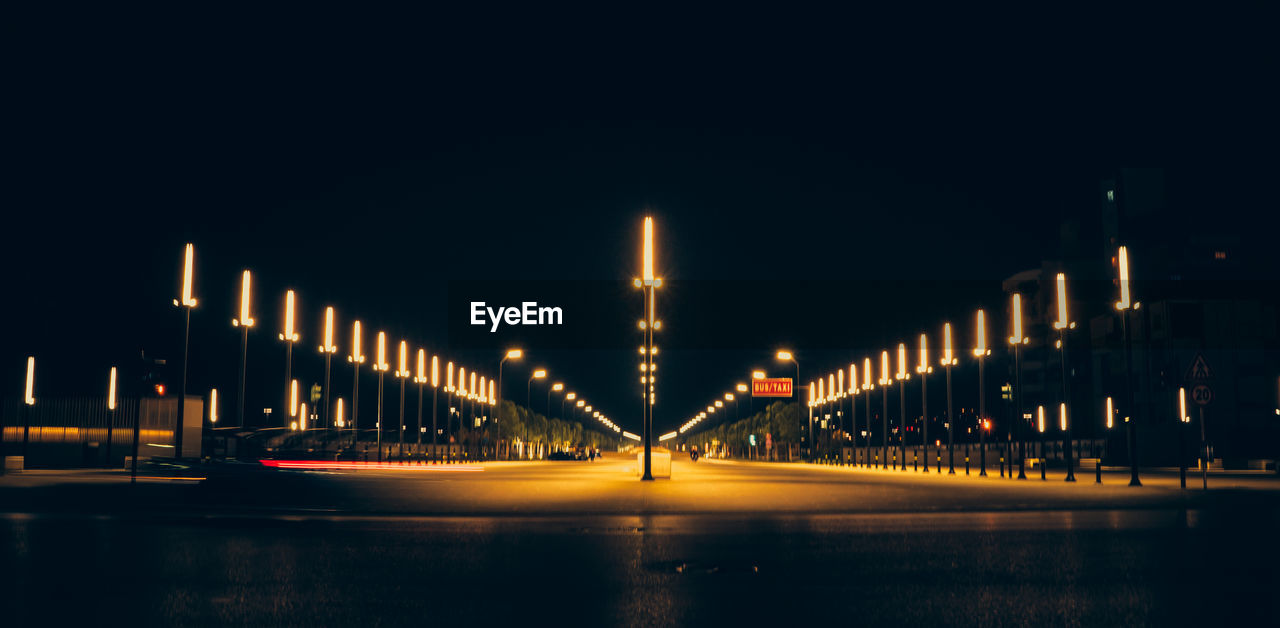 Illuminated bridge over river against sky at night