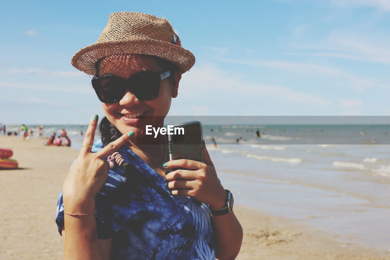 Portrait of mature woman holding mobile phone at beach