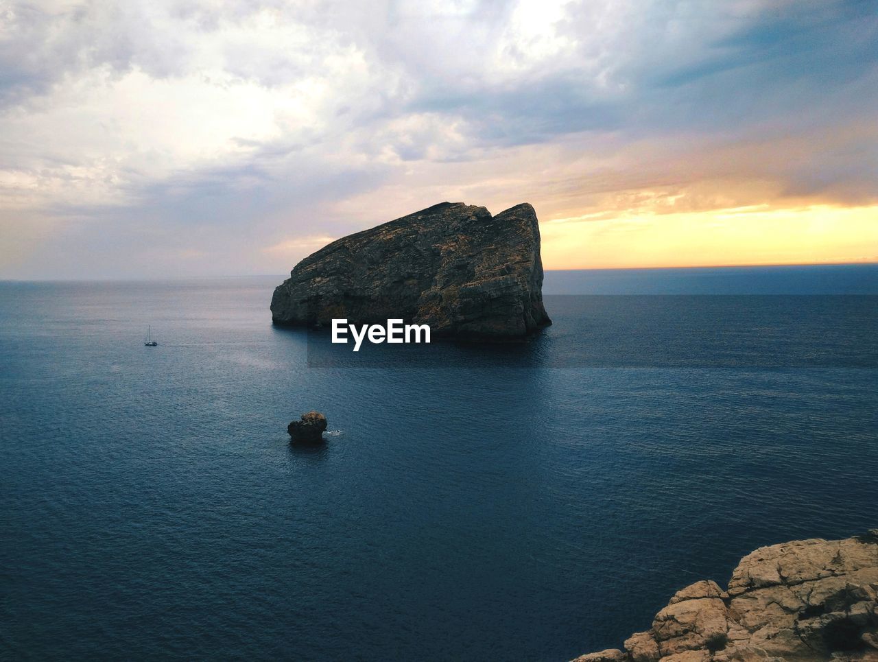 ROCK FORMATIONS IN SEA AGAINST SKY DURING SUNSET