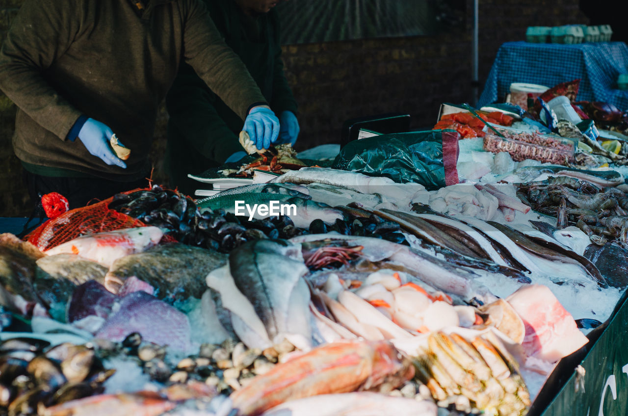 Midsection of vendor arranging fish for sale at market