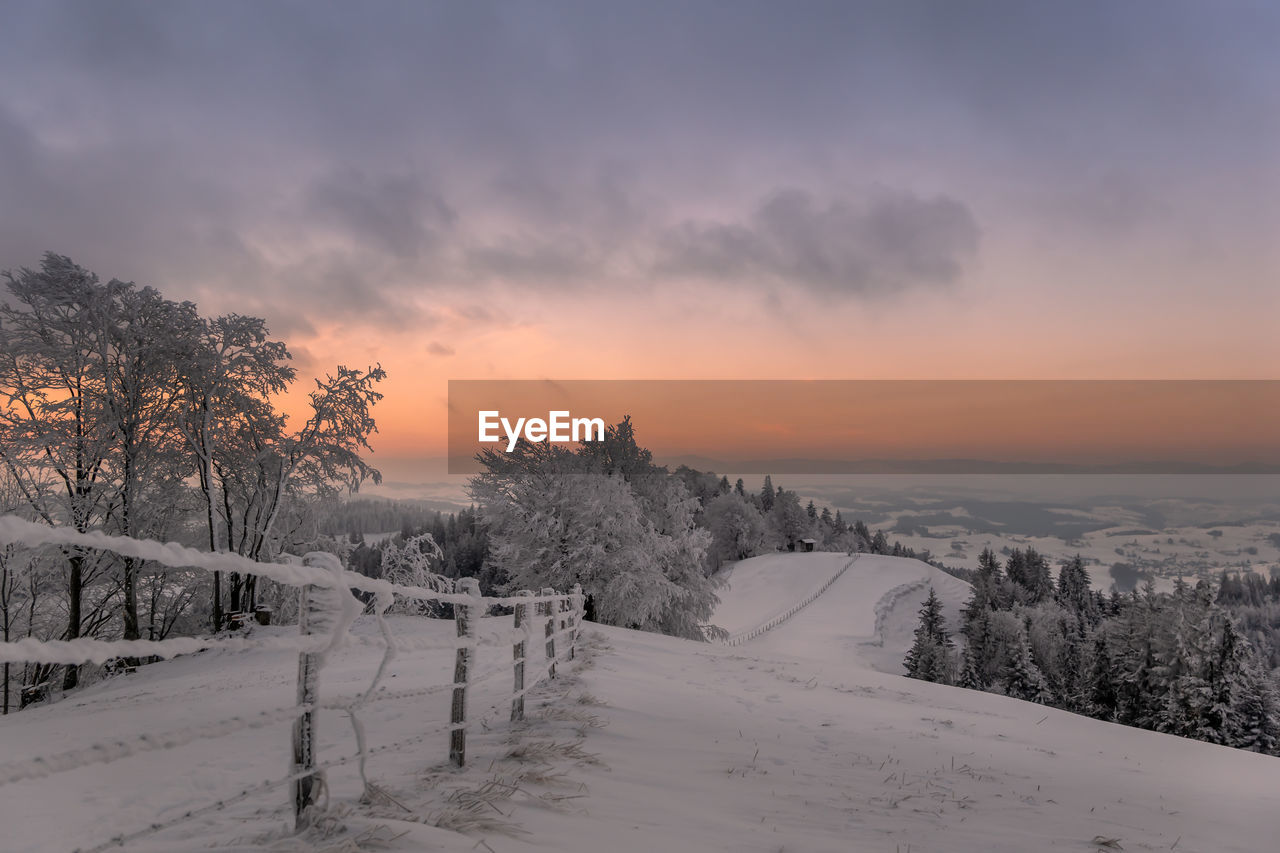 Scenic view of snow covered field against sky during sunset