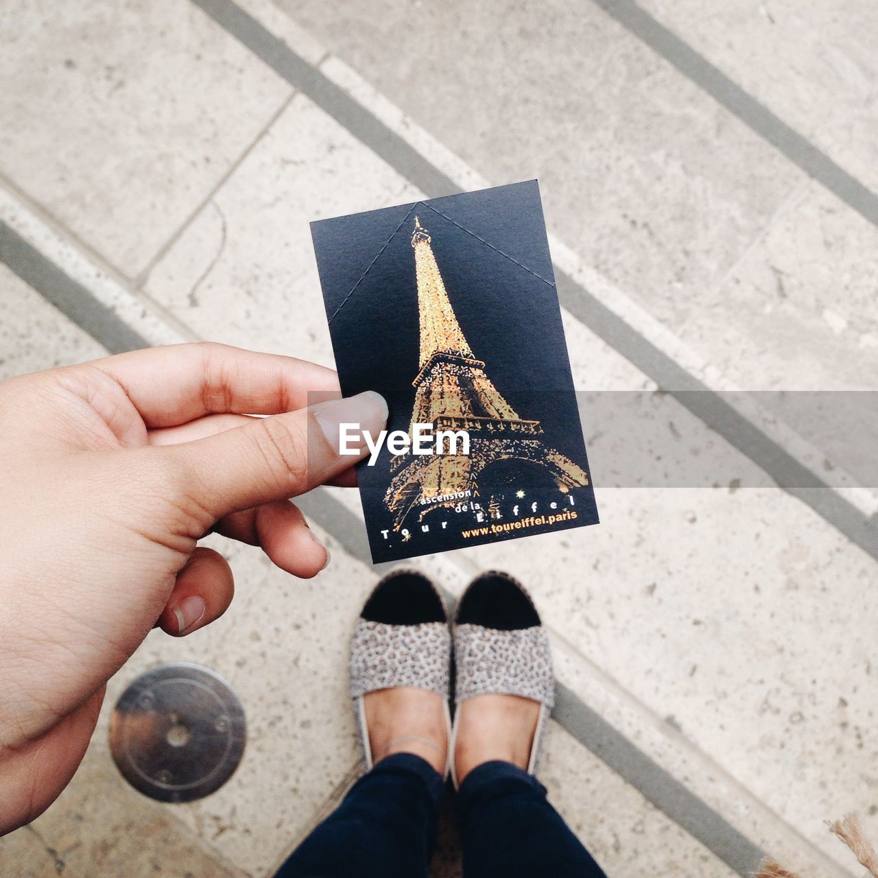 Low section of woman holding photograph with eiffel tower