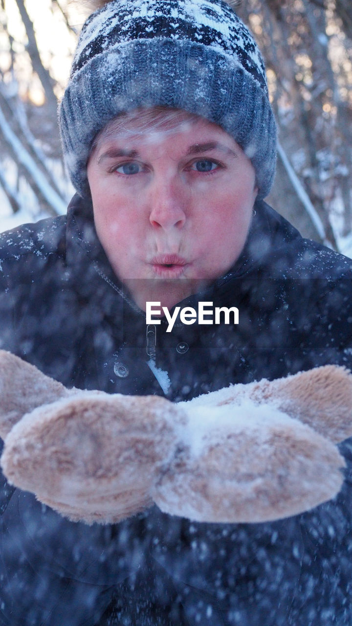 Portrait of woman blowing snow into the camera 