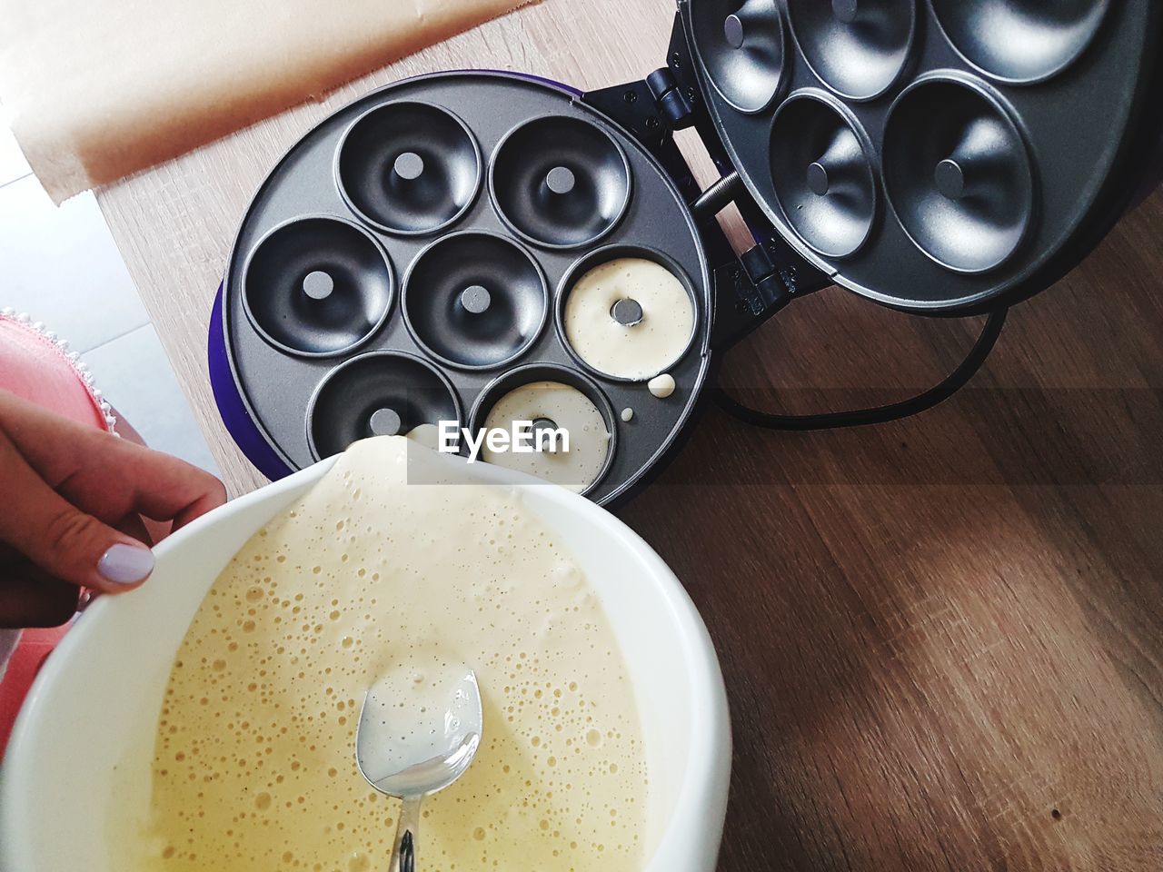 Cropped hand of woman pouring batter in container at table