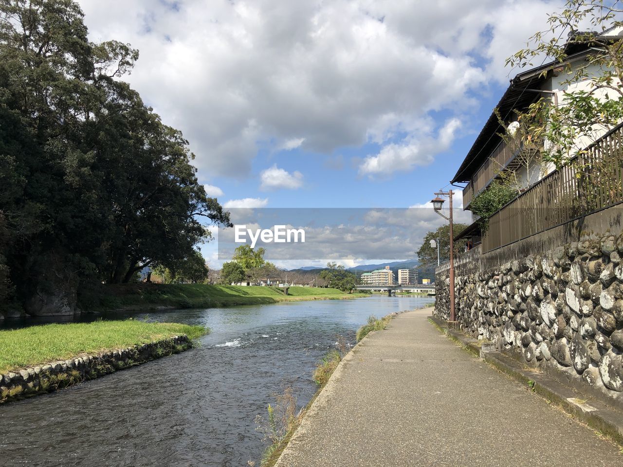 Road by canal amidst buildings against sky