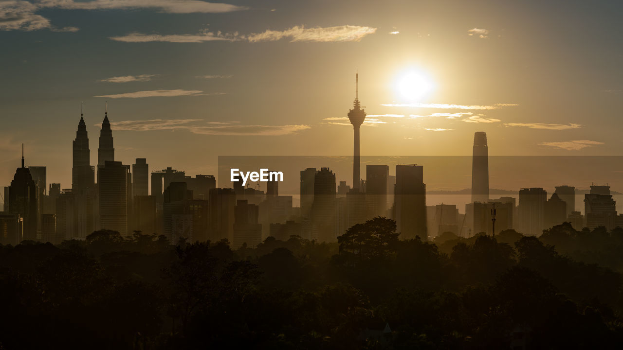 Modern buildings in city against sky during sunset