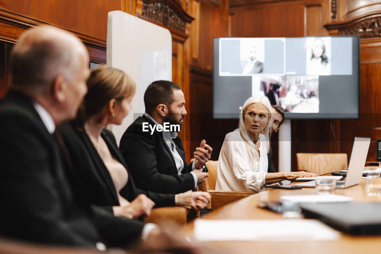 Female financial expert discussing with colleagues in meeting at board room