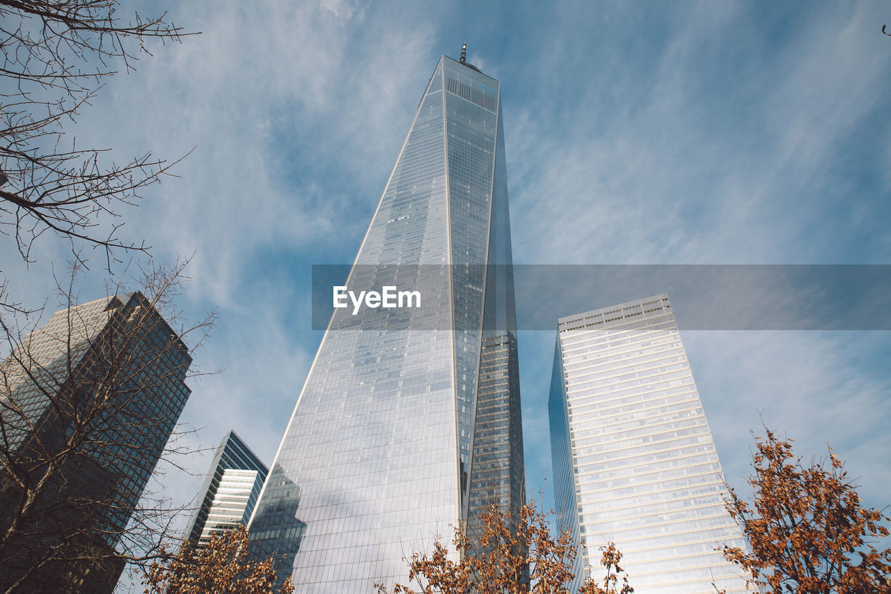 Low angle view of one world trade center by modern buildings in city against sky
