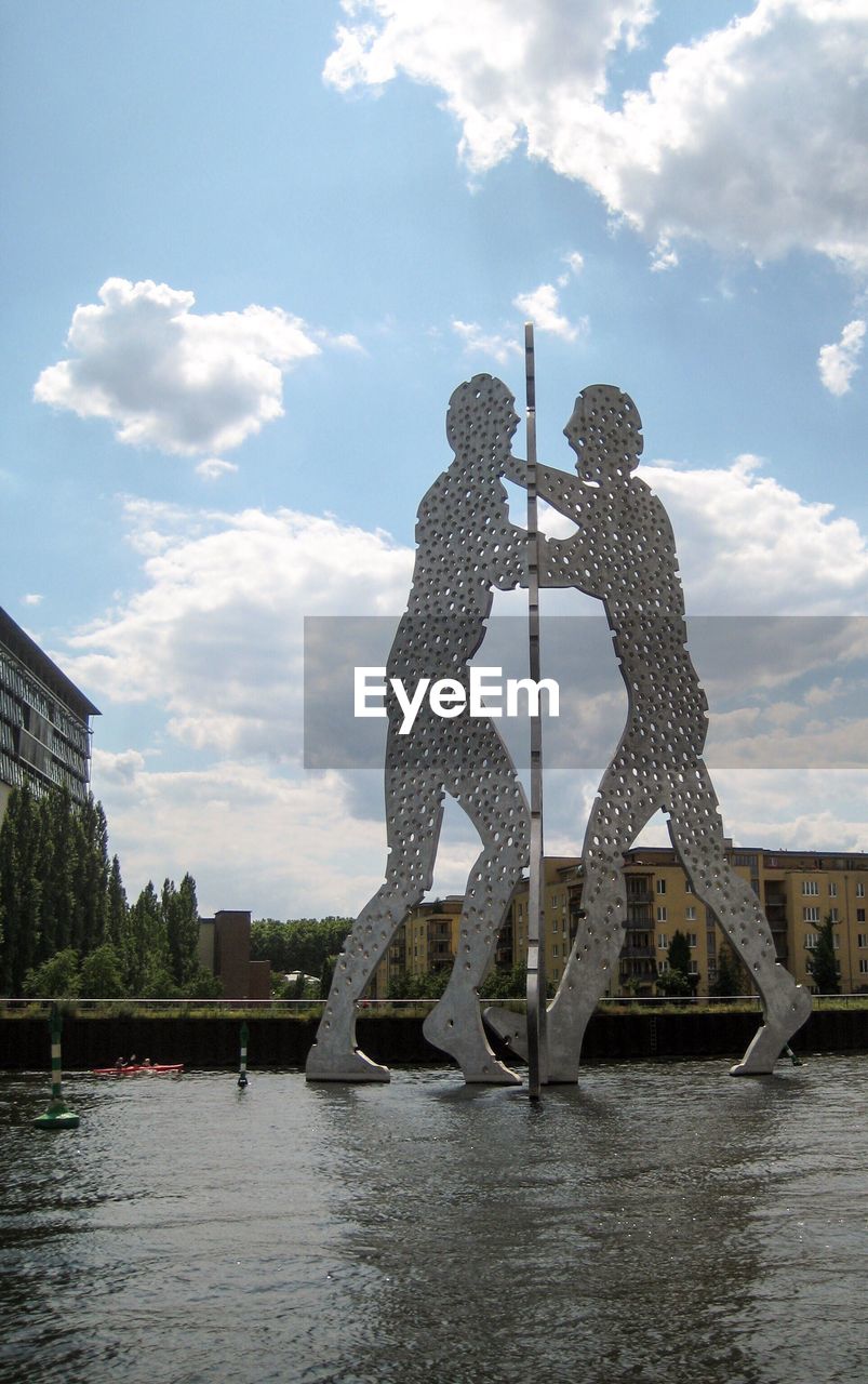 Sculpture in river against sky in city