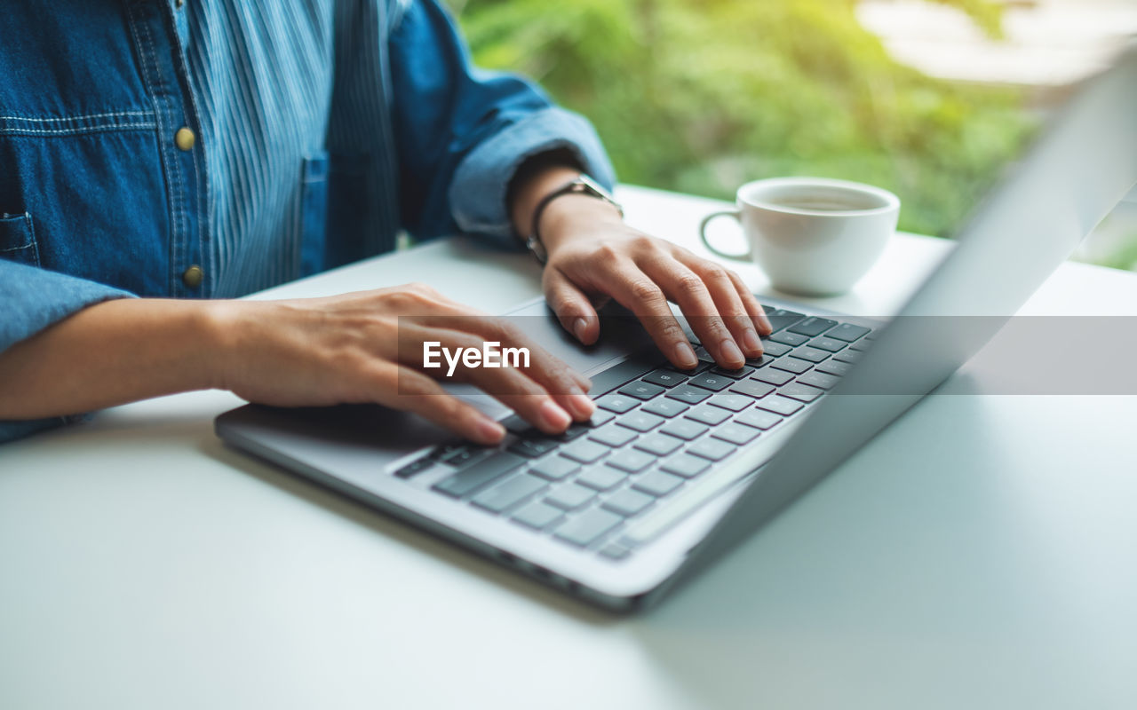 midsection of woman using laptop at table