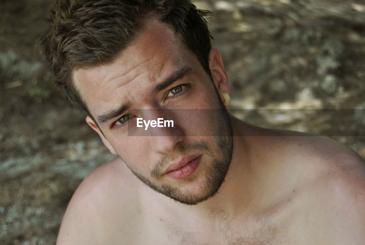 Close-up portrait of shirtless young man with stubble