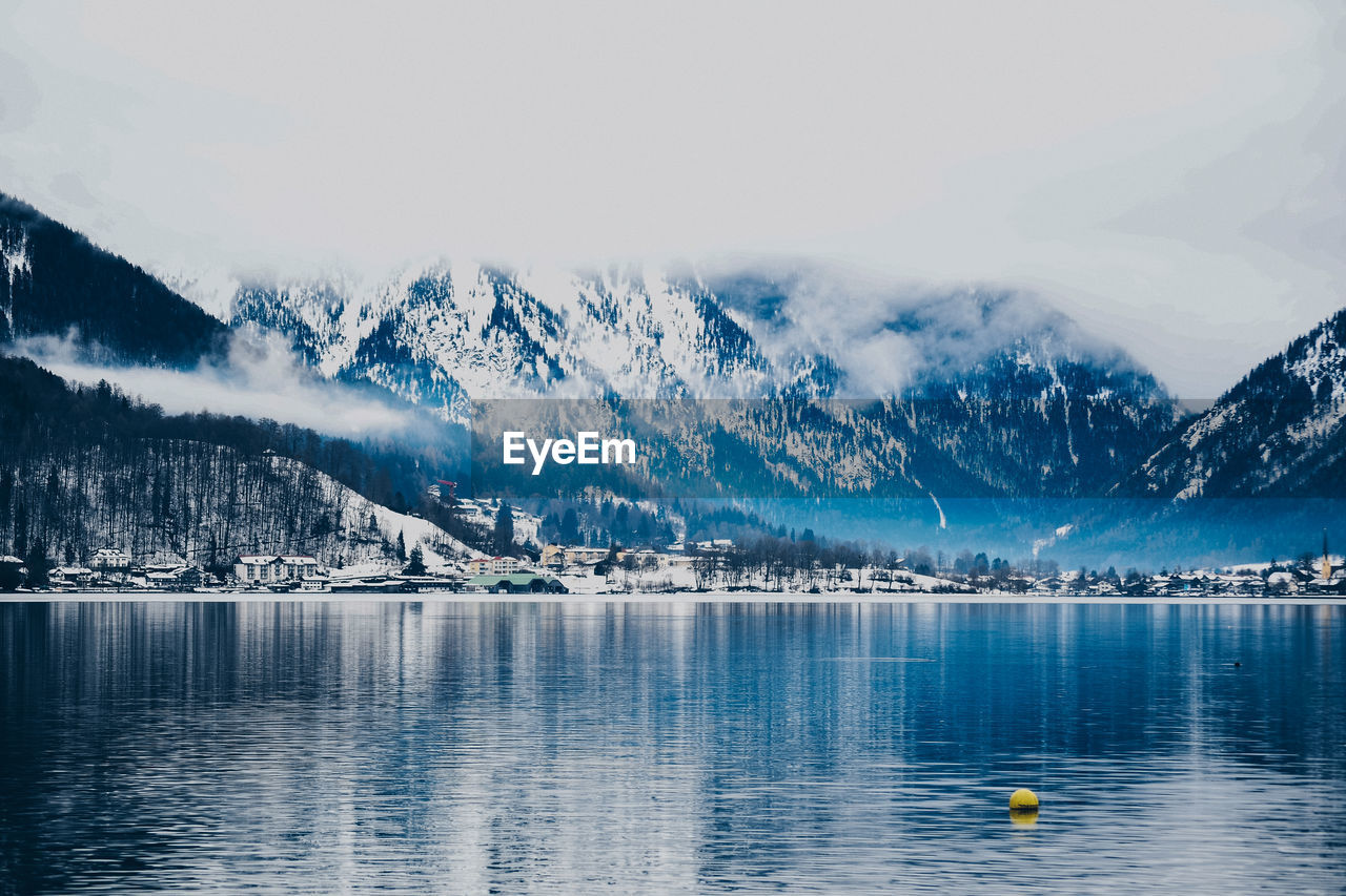 Scenic view of lake by snowcapped mountains against sky