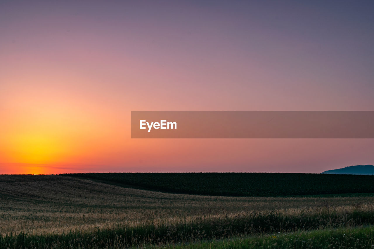 SCENIC VIEW OF FARM AGAINST SKY DURING SUNSET