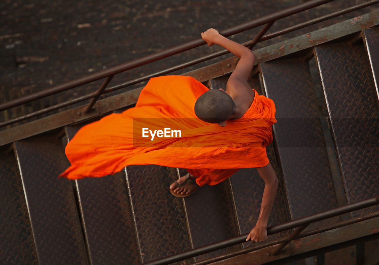 High angle view of monk walking down metallic steps