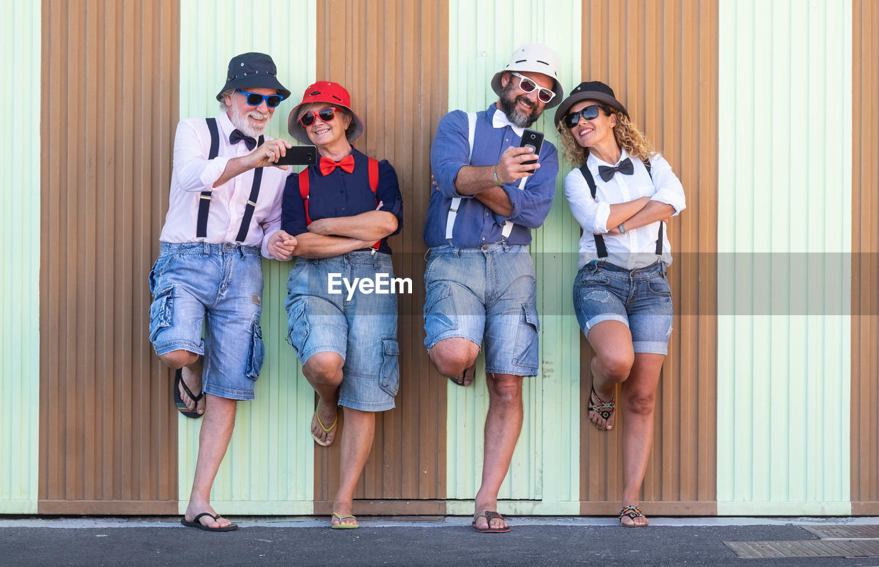 Smiling family using mobile phone while standing against corrugated iron