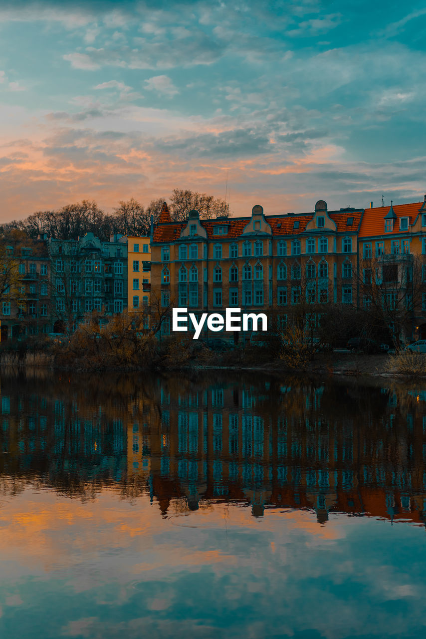 Reflection of building in lake against sky during sunset