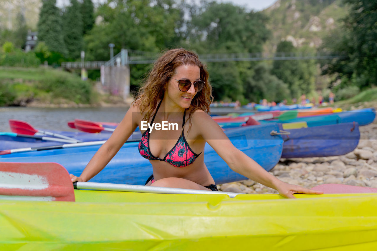 portrait of young woman swimming in boat on lake