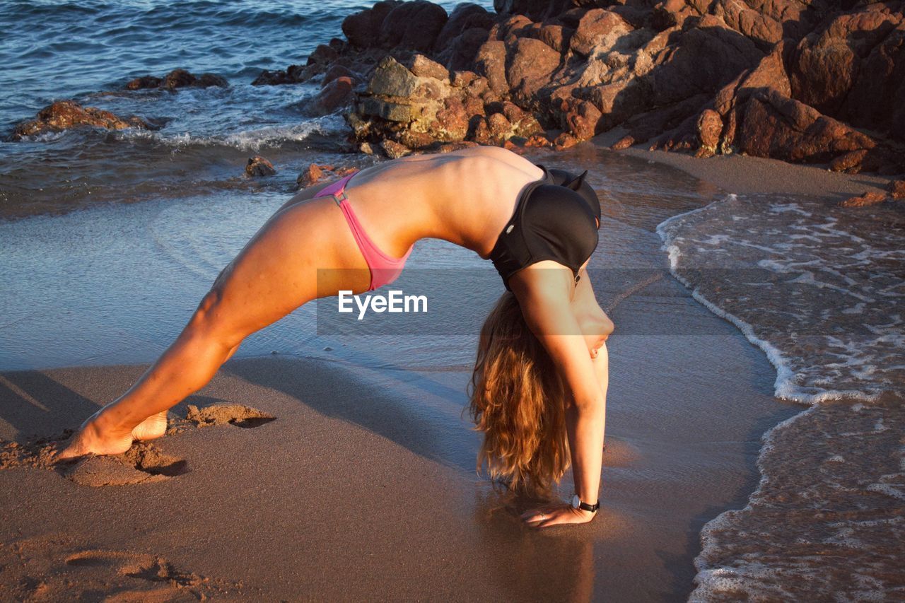 Sensuous woman exercising on sand at beach