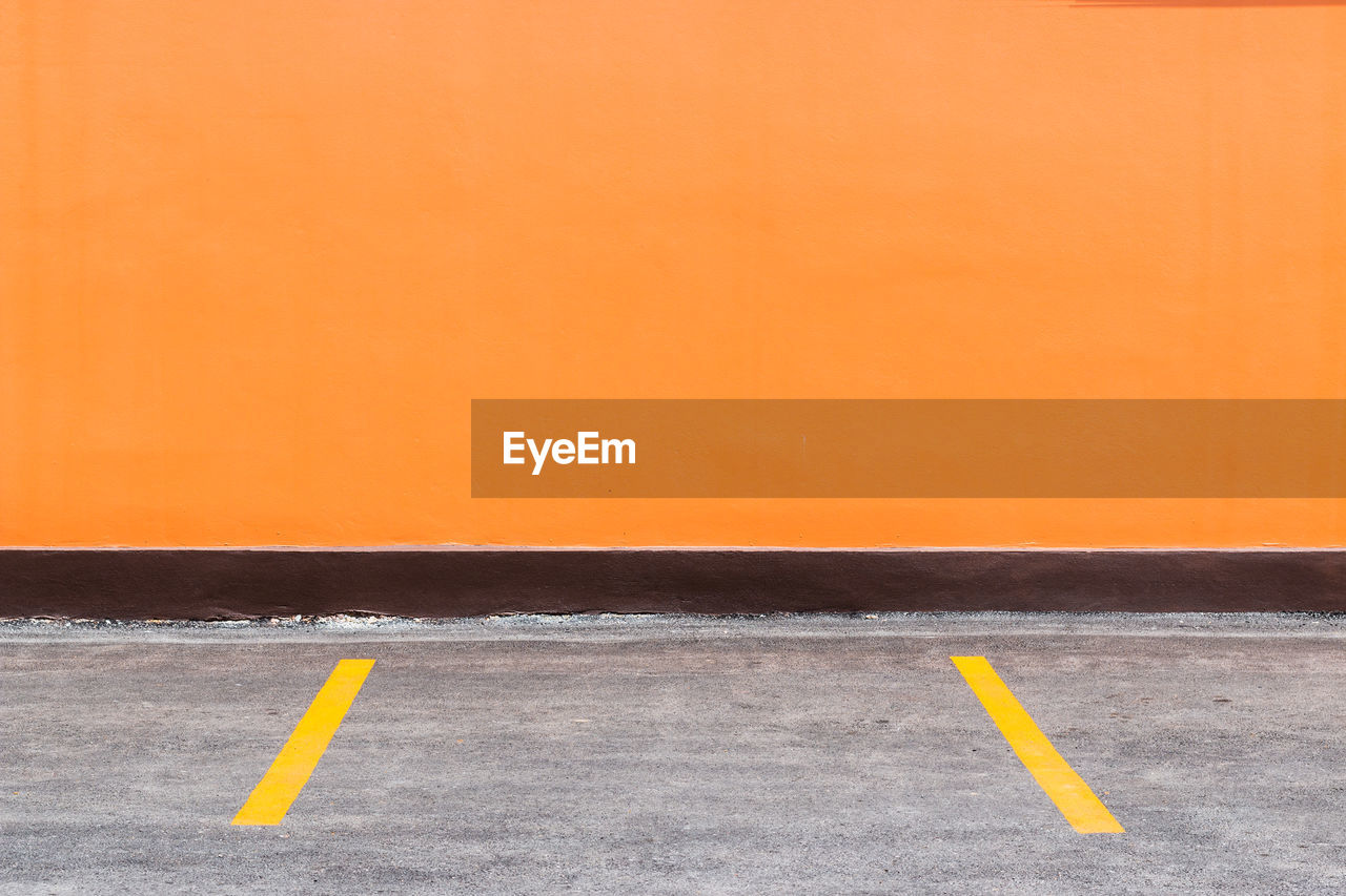 Orange building wall and parking spaces with painted yellow dividers